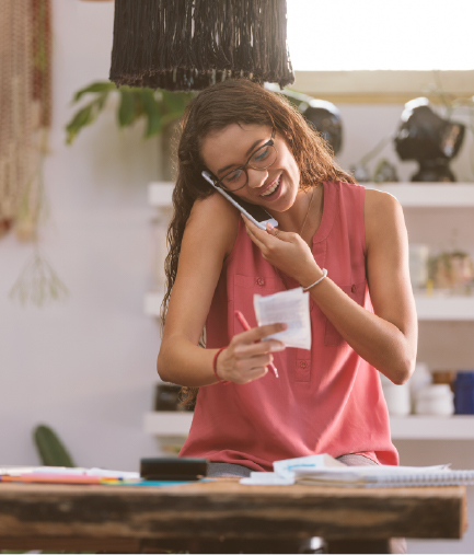 woman talking on phone looking at a note on paper