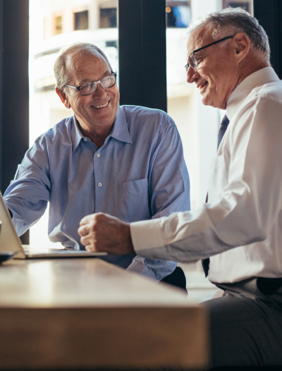 Two businessmen smiling while looking at a laptop