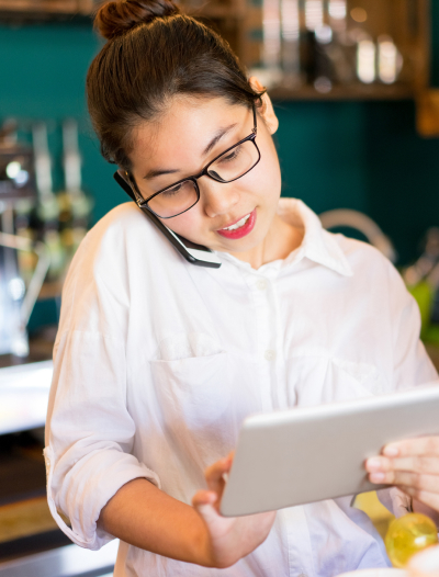 Business owner talking on the phone while looking at a tablet