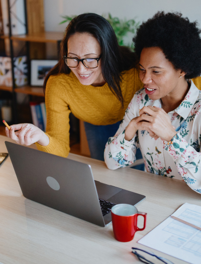 Two woman looking at a laptop and smiling